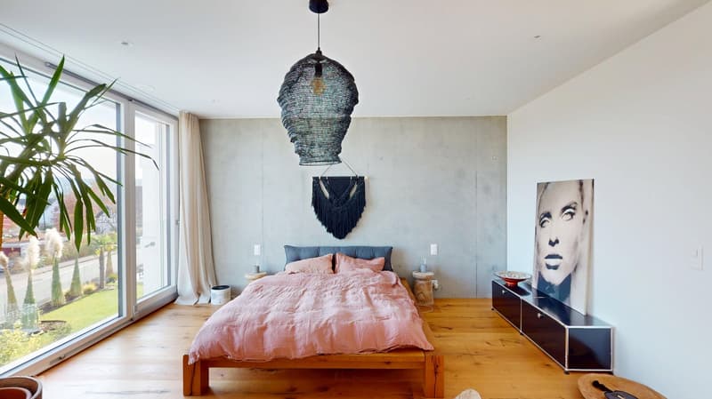 a bed with pink sheets, wooden headboard, two nightstands, large window with a view of outside