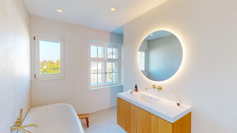 bathroom with bathtub, sink, mirror, wooden cabinet, windows, and natural light