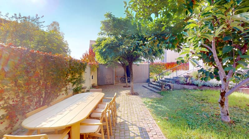 Wooden table and chairs, brick path, trees, building, plants