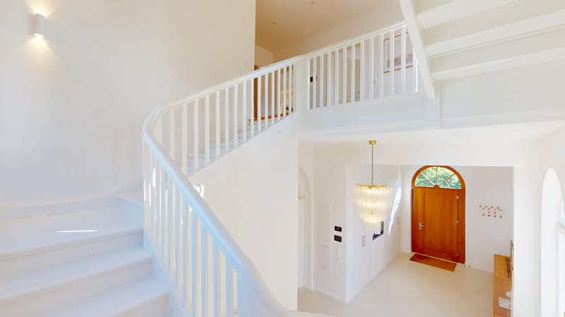 White modern entrance, white staircase, white railings, chandelier, wooden door
