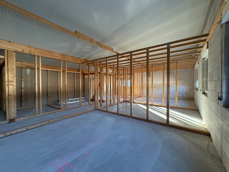 skeleton structure, concrete floor, exposed beams, unfinished walls, windows, wire on the ground
