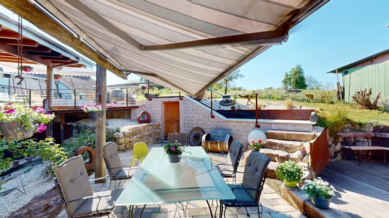 glass table with chairs, patio umbrella, potted plants, steps, barrel, wood door, wooden railings, elevated seating area, and a grassy view