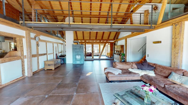living space with open-plan kitchen, fireplace, large brown leather sofa, large windows, wooden flooring