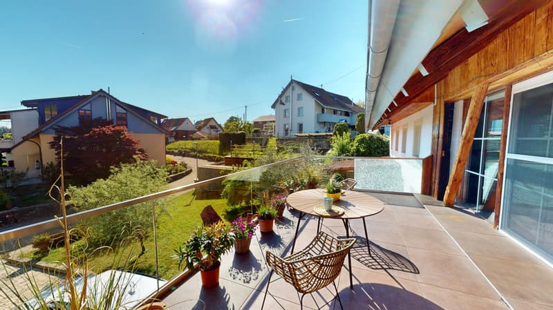 Wooden balcony with tiled flooring, table and chairs, potted plants, glass railing, view of the neighborhood