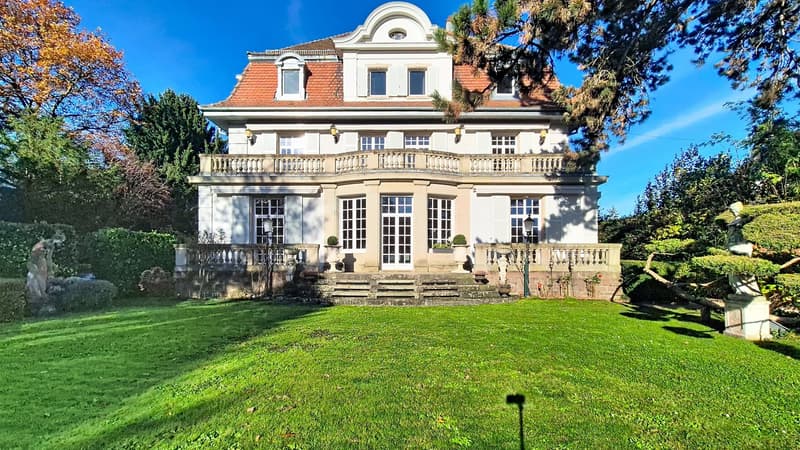 2-story house, white exterior, red roof, large bay windows, balcony, well-kept garden, decorative trees