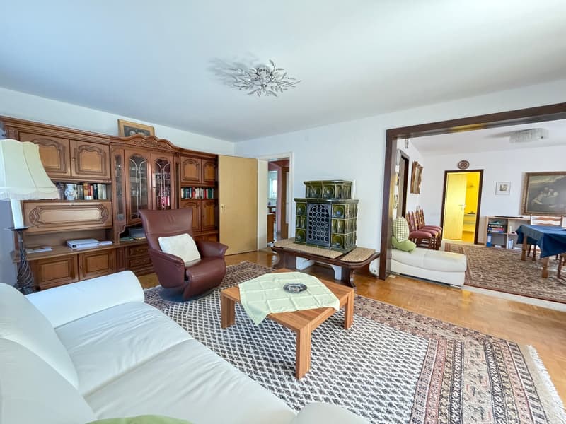 white couch, wooden coffee table, brown armchair, wooden cabinet, fireplace, wooden floor, white walls