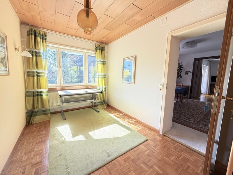 empty room with wooden floor, beige carpet, desk, radiator, curtains, picture frame, lamp, mirror, open door