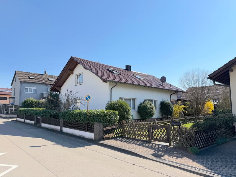 Detached house, brown roof, white walls, fenced garden, shrubs, wooden fence, street sign