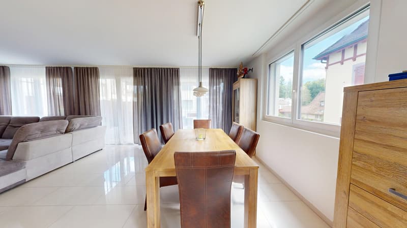 Dining room with wooden table and chairs, white tiled floor, large windows, couch, wooden cabinet, pendant light