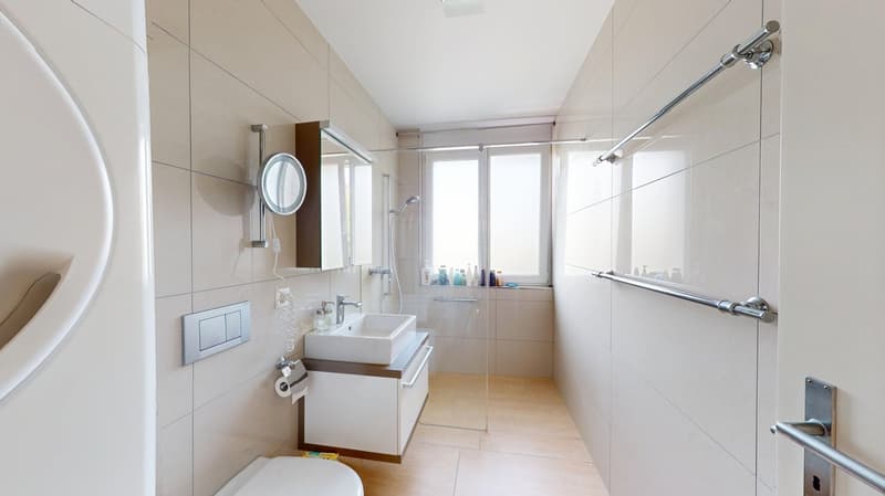 modern bathroom with white tiles, glass shower enclosure, white sink, toilet, and vanity with storage, wall-mounted mirror, and power outlet