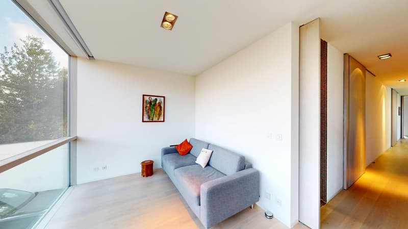 modern living room with large windows, gray couch, wooden floor, picture frame on the wall