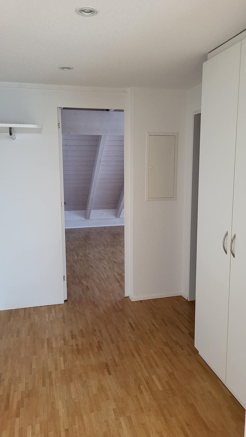 Empty room with wooden floor, open door, and closet