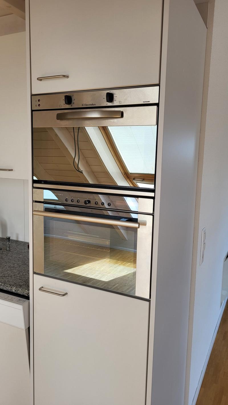Modern integrated stainless steel oven, granite kitchen counter, white cabinets