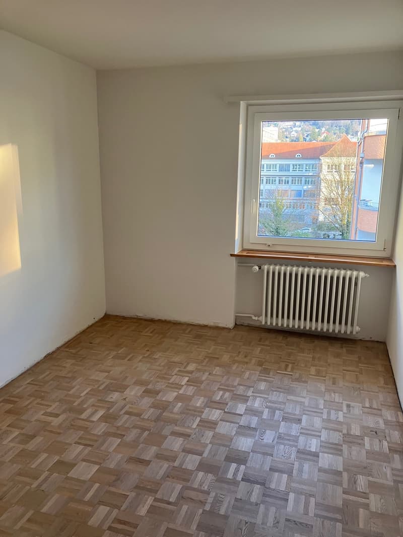 Empty room, white walls, wooden parquet floor, large window with wooden frame