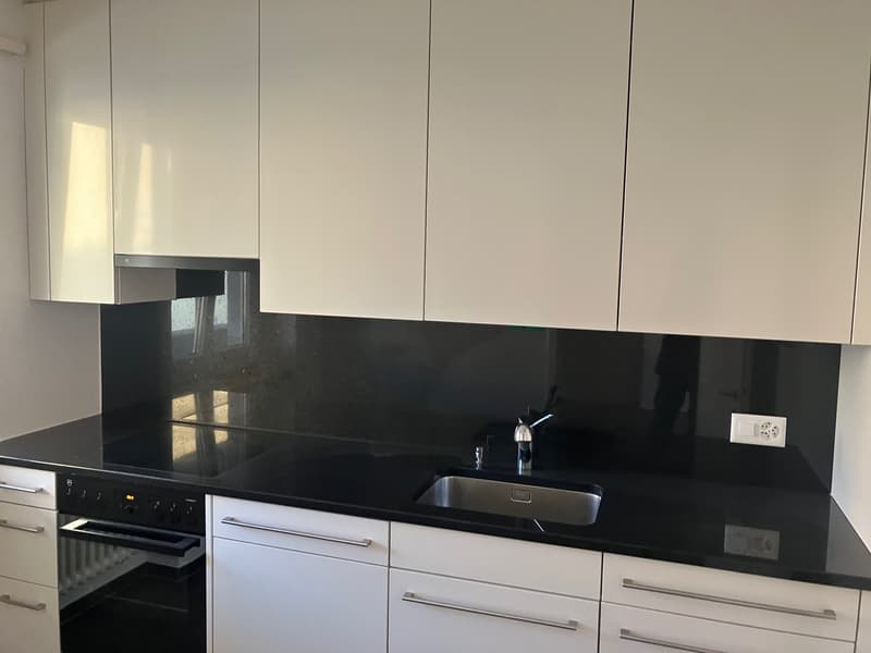 modern kitchen, white cabinets, black countertops, stainless steel sink, gas stove, built-in oven, extractor hood, electrical outlet