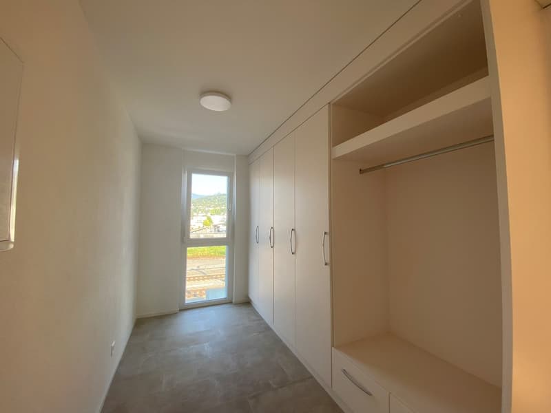 Empty room with a glass door, built-in wardrobes, tiled floor, a round ceiling light.