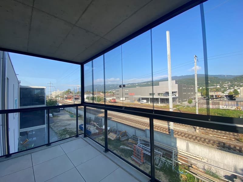 modern apartment with large windows, overlooking railway tracks and surrounding area