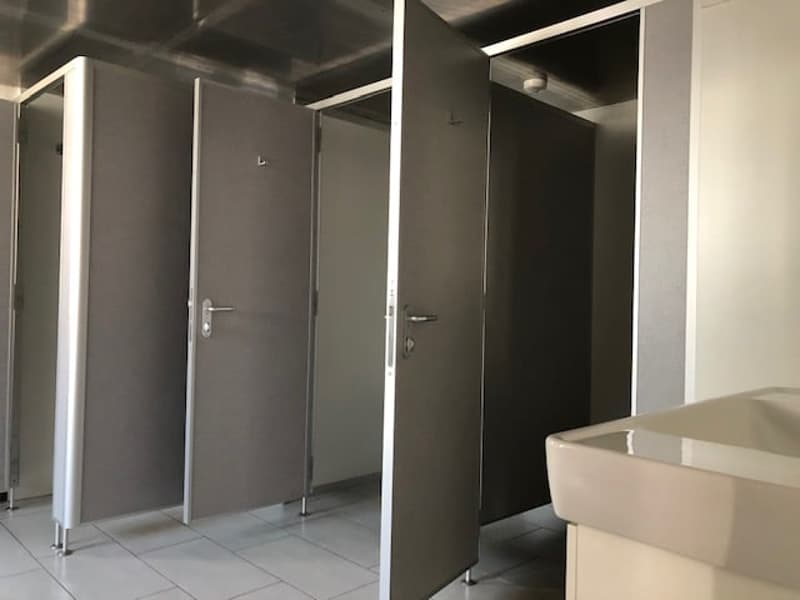Three stalls with doors, mirror, sink, white tiles