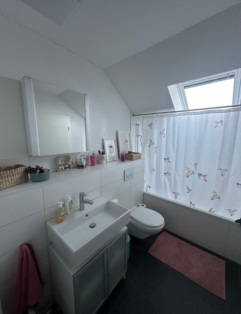 Bathroom with white tiles, white sink, white toilet, white bathtub, white shower curtain, white mirror, white cabinet, pink rug, white shelves, basket, bowl, and various items on the shelves.