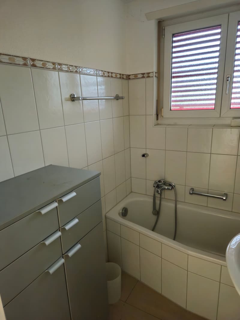 Bathroom with bathtub, cabinet, window, tiled walls and floor