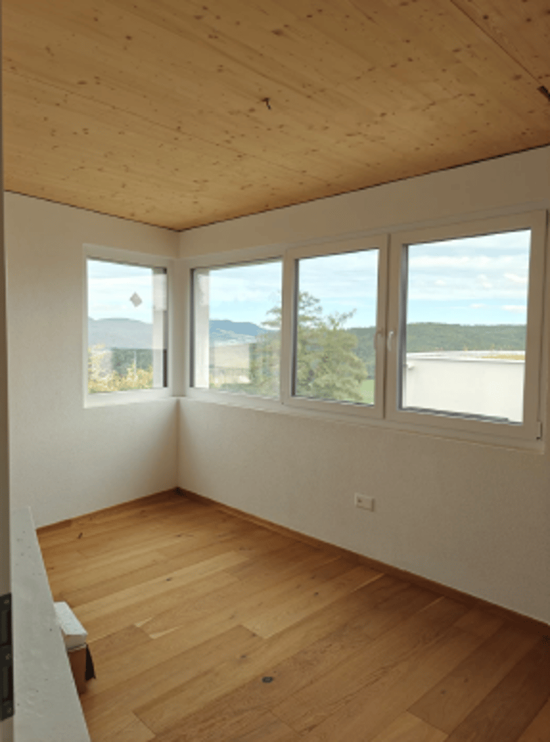 wooden floor, white walls, three windows, mountains view