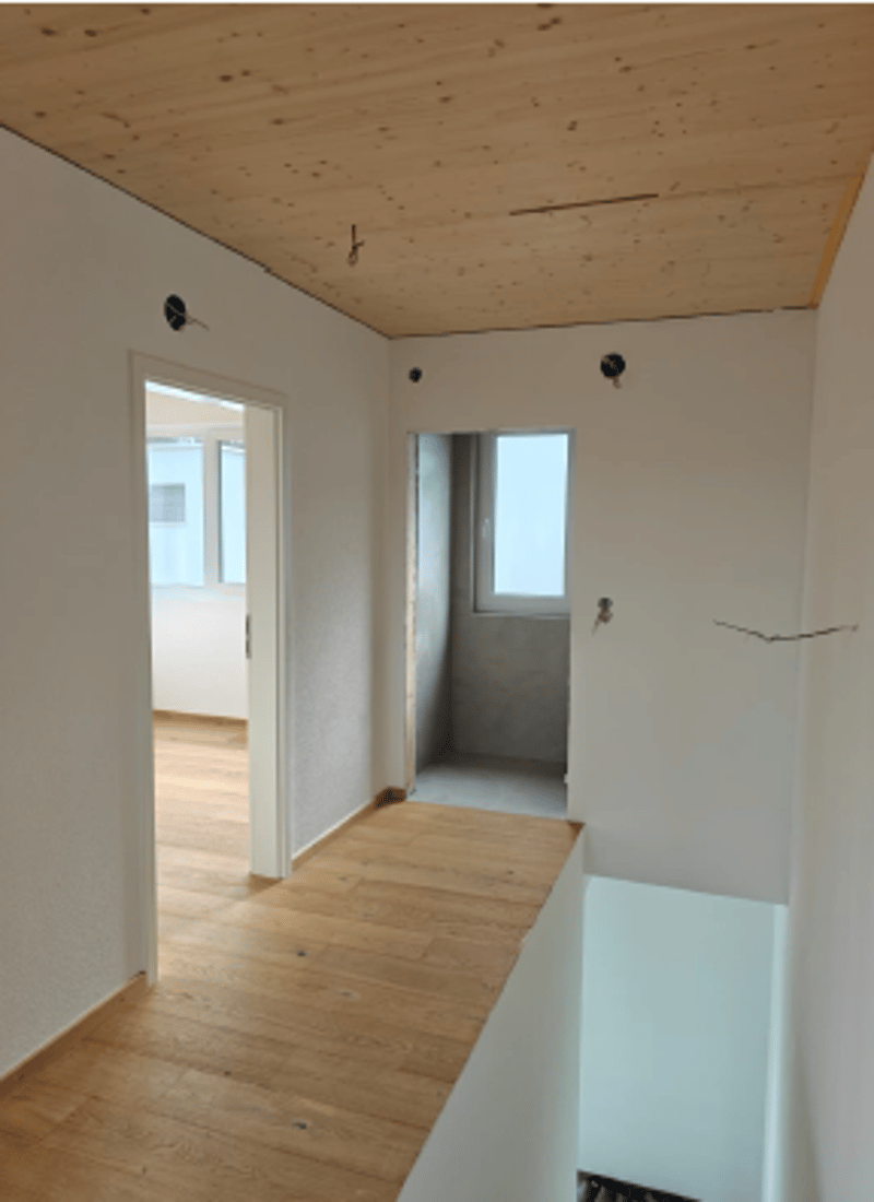 Empty room with wooden floor, stairs, glass window, white walls, wood ceiling