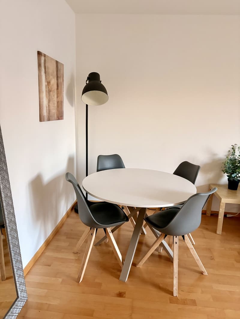 round white table, 4 grey chairs, lamp, mirror, painting, potted plant
