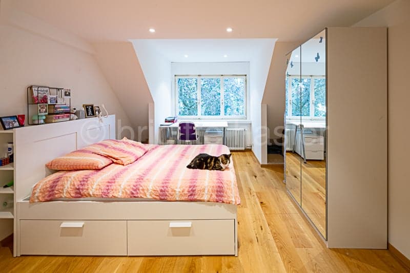 Spacious bedroom with hardwood floors, large windows, built-in storage bed, and mirrored wardrobe closet