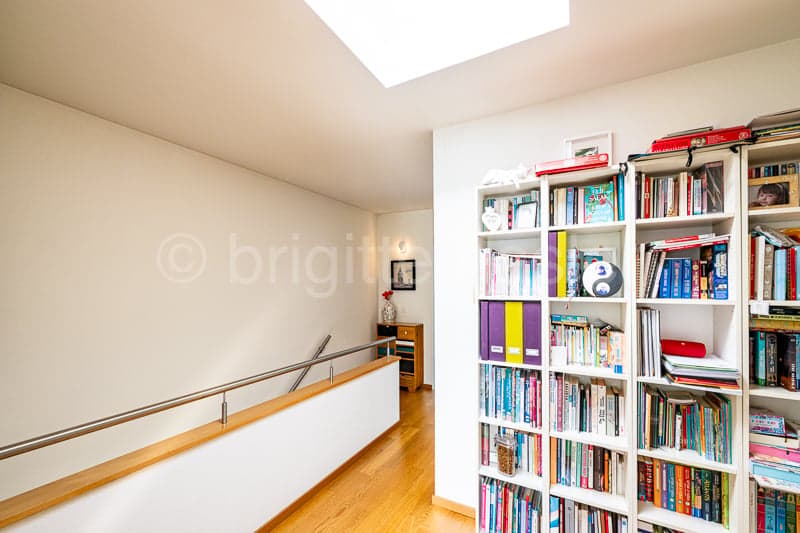 wooden floor, white walls, metal railing, bookshelf, skylight
