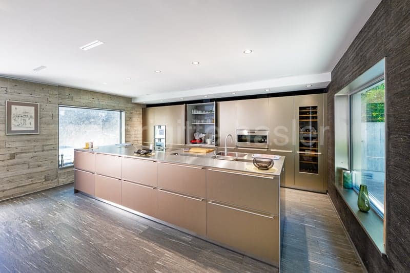 modern kitchen with island, wooden floor, large windows, stainless steel appliances