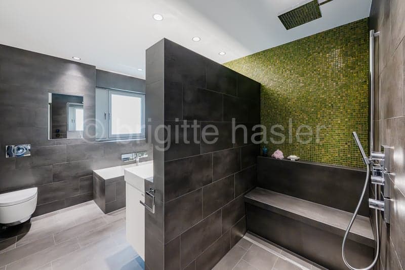 white porcelain fixtures, walk-in shower with green mosaic wall, built-in bathtub, white sink, mirror, toilet