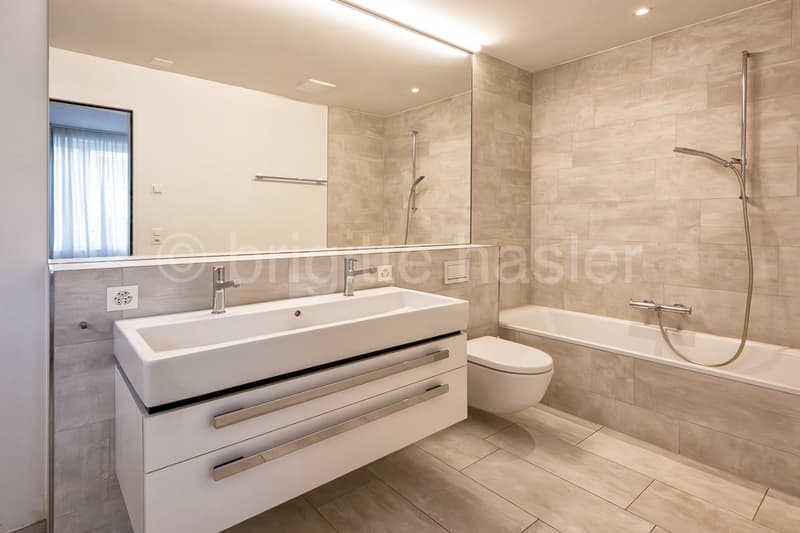 modern bathroom with white sink, bathtub, toilet, and shower