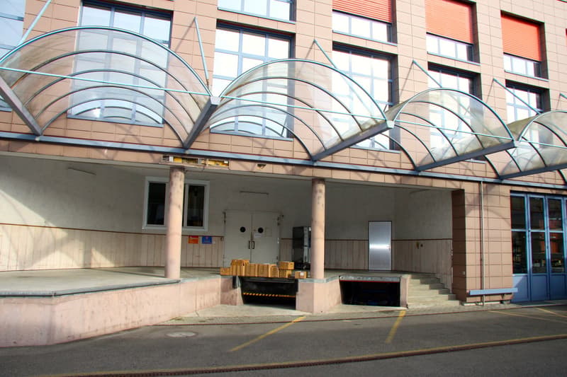 building with car parking facility, multiple glass windows, arched canopy, double doors