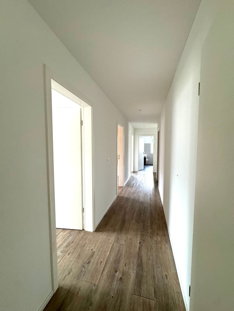 Empty hallway with wooden flooring and white walls