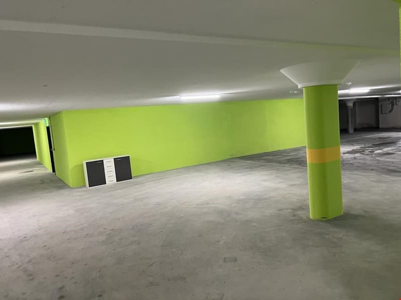 empty parking area, lime green wall, grey concrete floor, fluorescent lighting, grey lockers