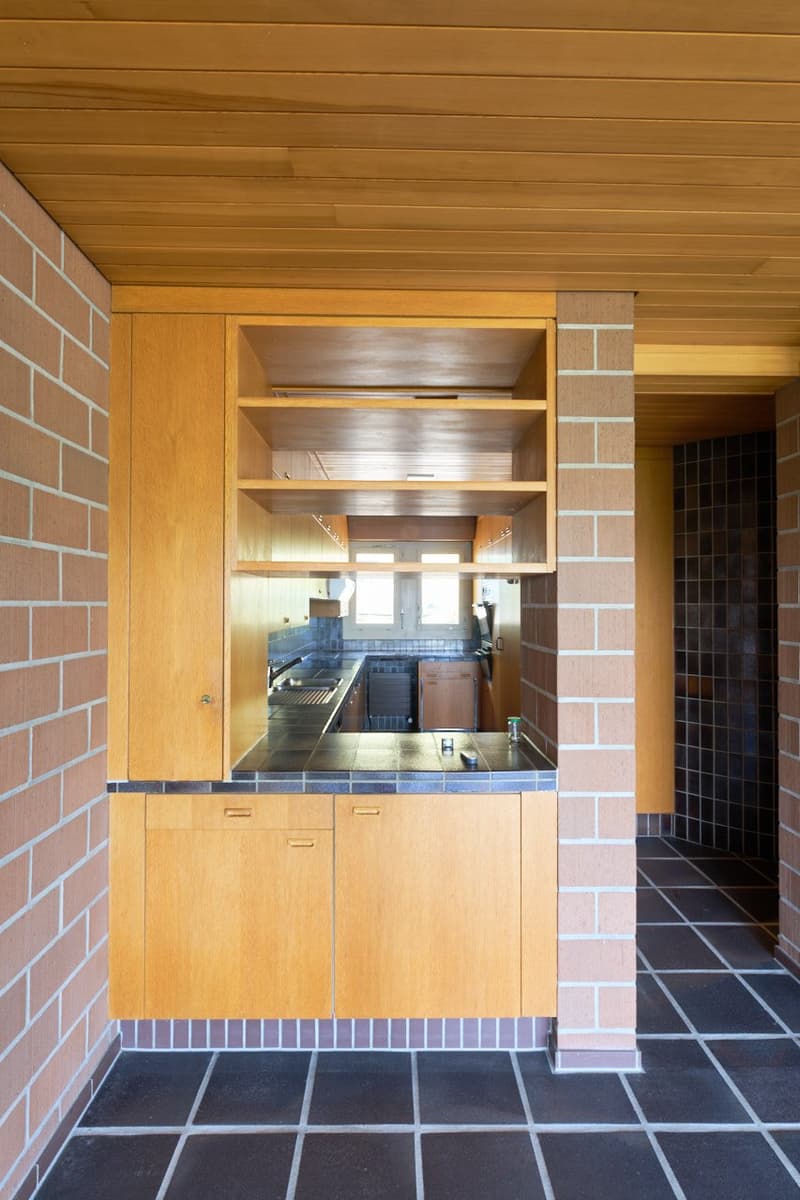 Wooden cabinets, tile countertop, built-in shelves, tile flooring