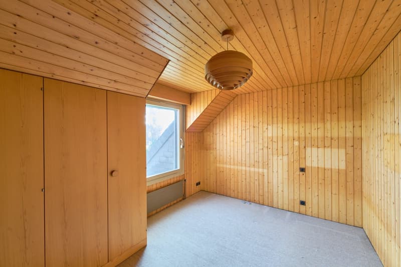 Wooden paneled room with a large circular light fixture, a window, and a closet or cabinet on the wall.