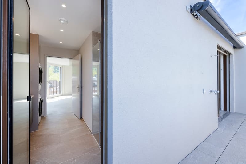Entrance hallway, tile floor, glass doors, white walls, ceiling lights, washing machines, large windows