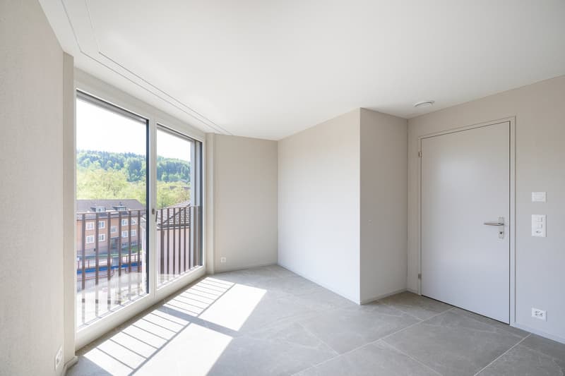 open layout, large glass doors leading to balcony, modern tile flooring, white walls, no furniture