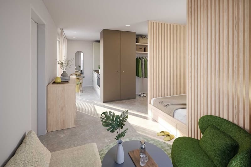 living room with couch, table, and green plant, bedroom with bed and built-in closet, open kitchen with table