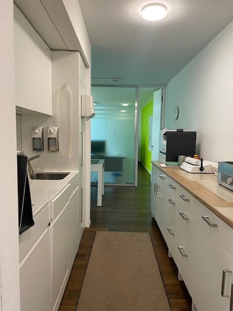 modern kitchen with white cabinets, wooden floor, sink, faucet, countertop, appliances, rug, open door