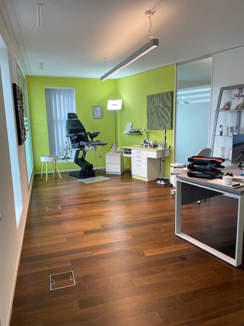 office room with wooden floor, green wall, desk, chair, lamp, monitor, stool