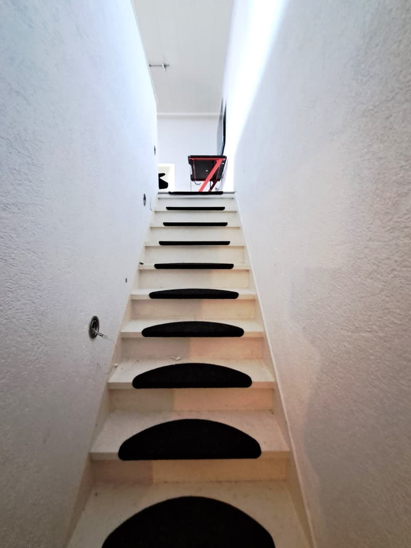 White staircase with black carpeted steps, leading up