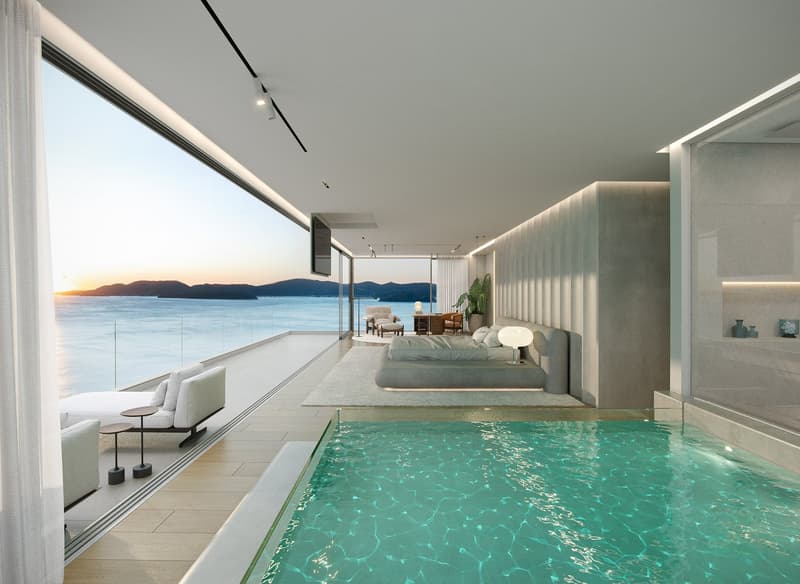 Modern room with large windows, balcony, swimming pool, bed, sofa, desk, and a view of the ocean