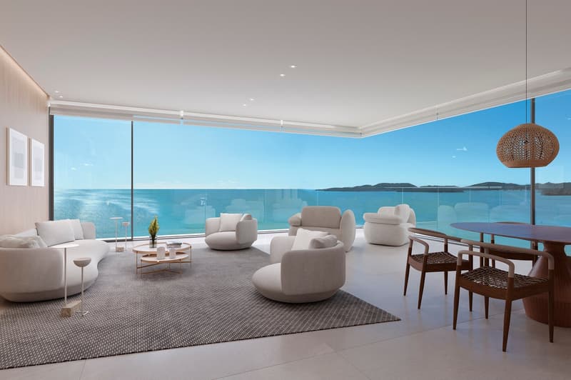 modern living room with large windows, white furniture, wooden table, ocean view