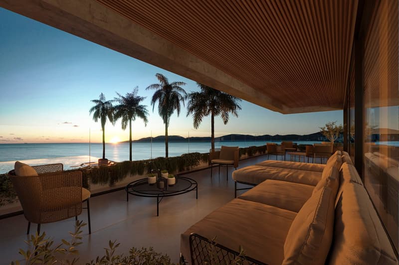 Outdoor terrace with a view of the ocean, lounge chairs, table, and palm trees