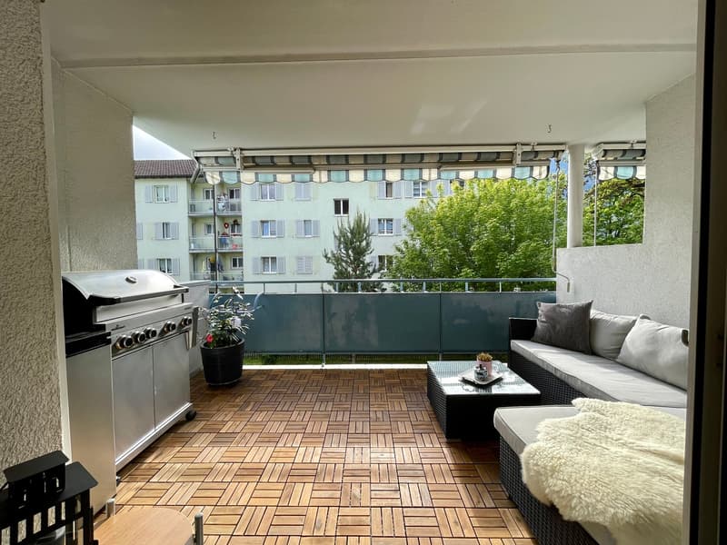 Balcony with wooden floor, metal railing, outdoor grill, potted plants, outdoor sofa, coffee table, fur blanket