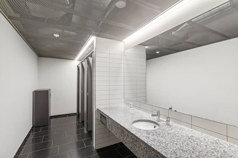 modern bathroom with white tiles, granite countertop, sink, mirror, and metal ceiling