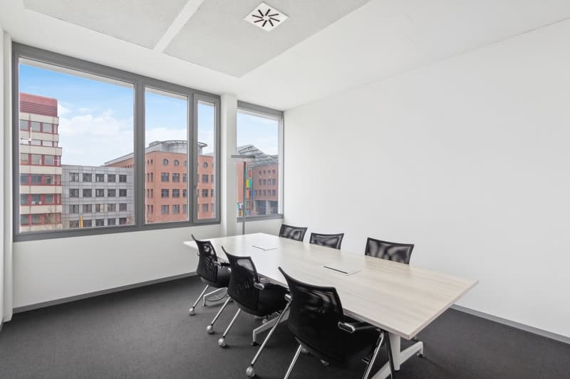 empty conference room with large windows, long table, black chairs, carpeted floor
