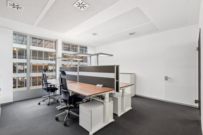 modern office with desks, chairs, and large windows
